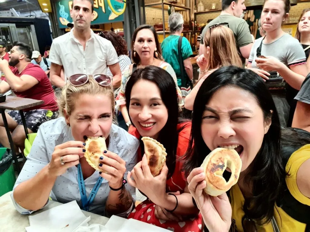 three women eating empanadas in buenos aires market
