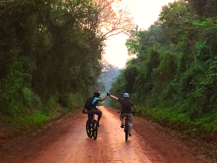 couple riding bikes, and clapping hands in the Jaguarete Trail, in Iguazu Falls.
