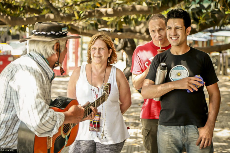 Street artist playing guitar for a family