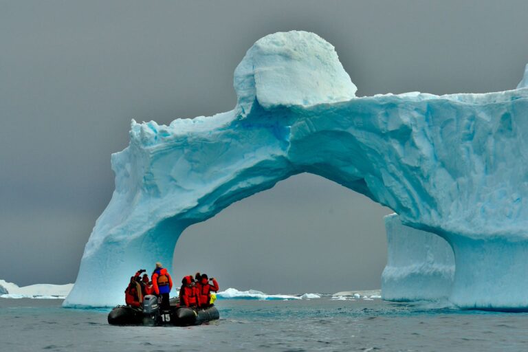 People sailing towards a big ice in Antarctica.