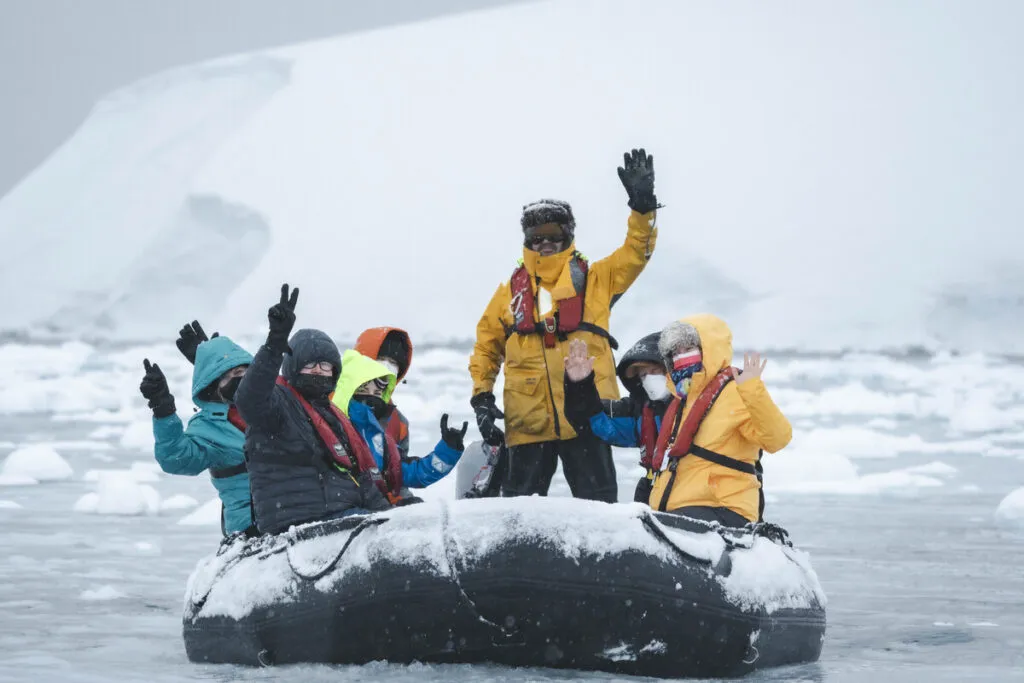 Group of people exploring antarctica in a zodiac