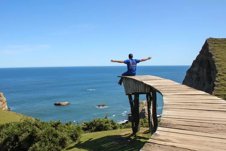 Man with open arms at the pier in Chiloé, Chile.